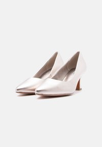 Paire d'escarpins argentés métalliques à bout pointu avec talons blocs de hauteur moyenne sur un fond clair uni.