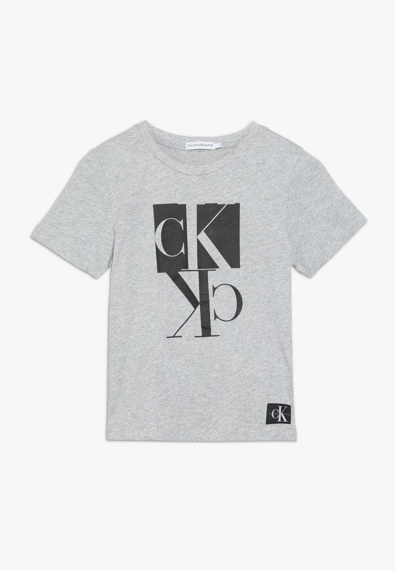 Grå bomulds t-shirt med korte ærmer, med et sort grafisk design med bogstaver og former. Inkluderer en sort logomærke ved kanten.