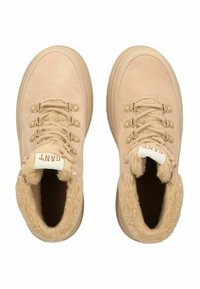 Beige suède sneakers met een zachte bontvoering, ronde neus en beige rubberen zool. Beschikt over zes veterogen en een logotab op de tong.