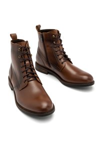Brązowe skórzane botki za kostkę o gładkiej fakturze, z fasonem na sznurowanie, bocznym zamkiem błyskawicznym i okrągłym noskiem. Widoczne detale solidnej konstrukcji.