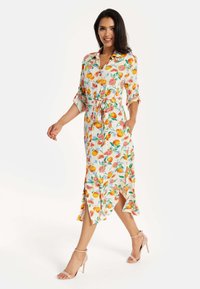 Floral dress featuring orange and pink fruit patterns, lightweight fabric, ankle-length with side slits, and a belted waist.