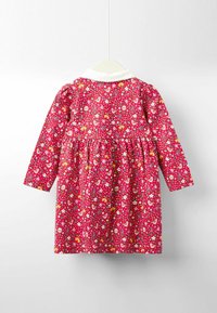 Rochie roșie cu flori, cu mâneci lungi, guler alb, talie strânsă, cu flori colorate și imprimeuri cu animale mici pe un material texturat.