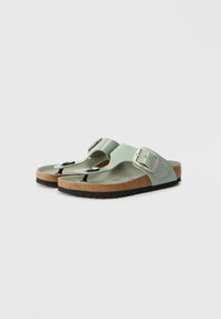 Ανοιχτό πράσινα σανδάλια με φελλούς σόλες, σχεδίαση T-strap, ρυθμιζόμενο ασημένιο κούμπωμα και υφή μαύρης καουτσούκ εξωτερική σόλα.