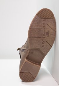 Brun støvle med tekstureret gummisål, der har en lav hæl, sidelukning med lynlås og et mærke "TOM TAILOR" på bunden. Størrelse 37.