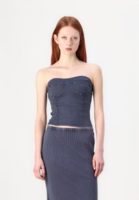 Top in denim senza spalline di colore blu scuro con un corpo aderente, texture a coste e dettagli di cucitura curvi. Abbinato a una gonna coordinata.