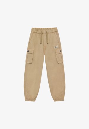 Pantalones cargo beige con cintura elástica, cordón ajustable, bolsillos laterales con solapa y botones de presión, y puños elásticos, con parche "No Limits" en el bolsillo derecho.