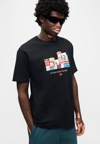 Μαύρο βαμβακερό t-shirt με πολύχρωμο γραφικό στοιχείο από στοιβαγμένα κουτιά στο μπροστινό μέρος, με το κείμενο «Είναι τι βρίσκεται μέσα που έχει σημασία.»