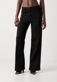 Black wide-leg jeans made of denim with a button closure, front pockets, and a smooth texture. Features a clean hem and minimal hardware.