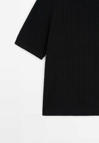 Mustat lyhythihaiset paita, joka on valmistettu teksturoidusta neuloksesta. Ominaisuuksina löysä fit ja ribbaus helmassa, yksivärinen ilman lisäkuvioita.