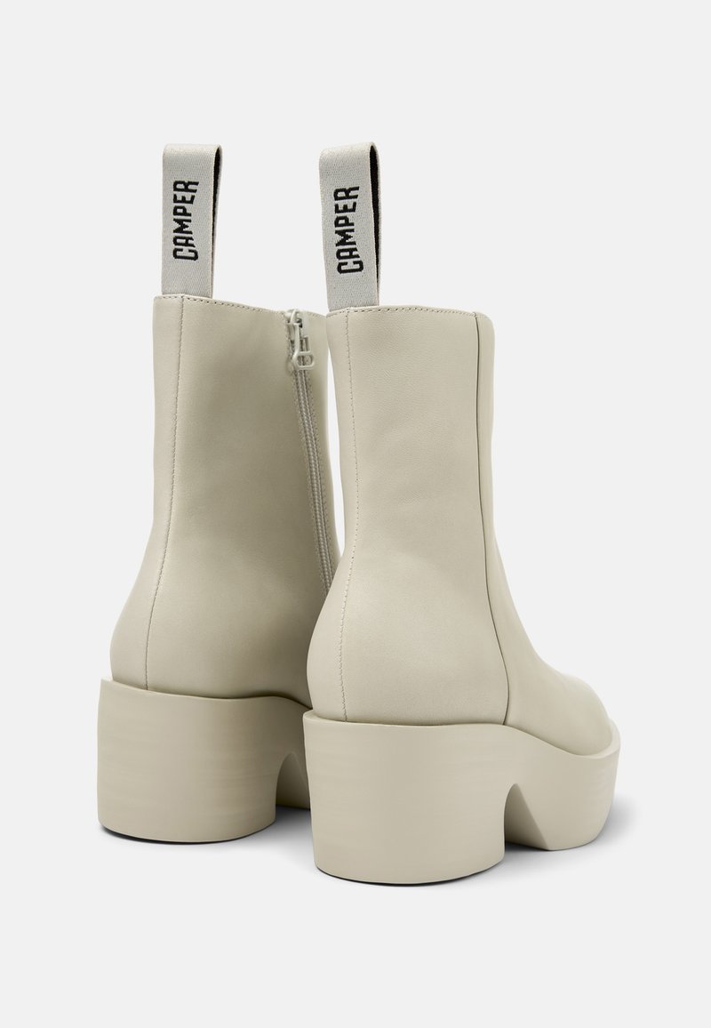 Beige plattform kängor med chunkiga klackar, sidoglädje och tygögon som är märkta "CAMPER."