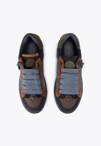 Une paire de baskets bleu marine avec des accents en suède marron et olive, des lacets larges bleu clair et des capuchons de orteils en caoutchouc texturé, vue d'au-dessus.