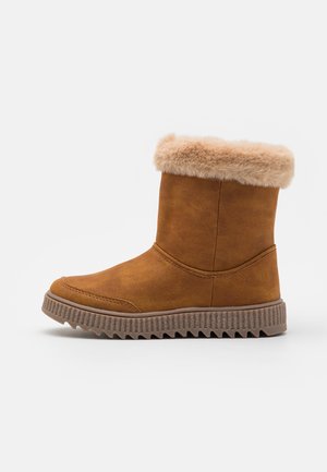 Bruine nep-suède enkelboot met een fluffy beige boord, een getextureerde rubberen zool en stiksel langs de voorkant.