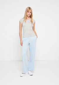 Γκρι εφαρμοστό κοντομάνικο μπλουζάκι σε συνδυασμό με ανοιχτό μπλε παντελόνι φαρδιάς γραμμής, με πλαϊνές τσέπες και λευκά αθλητικά παπούτσια. Απλή, καθημερινή εμφάνιση.