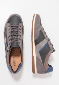 Baskets grises et bleu marine en suède et cuir, avec un bout arrondi, un design à lacets et une semelle en caoutchouc marron contrastante.