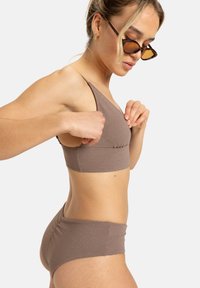 Ensemble bikini texturé marron avec un top triangulaire et un bas taille basse, présentant un léger éclat et un design minimaliste, porté par un mannequin.