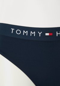 Námořnickomodré bikiny s kalhotkami, které mají měkký elastický pás s názvem značky "TOMMY" a akcentem červenobílé loga. Hladký povrch.