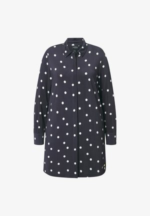 Löysä tumma paita, jossa on valkoisia pilkkuja, kauluspuseromalli ja pitkät hihat nappihihnalla. Sileä kangas, suora leikkaus.