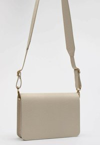 Borsa a tracolla beige con finitura in pelle sintetica testurizzata, hardware in tonalità oro e tracolla regolabile. Forma rettangolare con linee pulite.