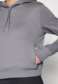 Grauer Hoodie mit weicher Textur, Kordelzugkapuze und gerippten Bündchen. Verfügt über eine Kängurutasche und ein verkürztes Design.