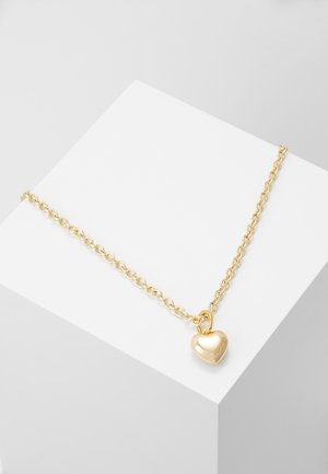 Collier en chaîne dorée avec un pendentif en forme de cœur. Le pendentif est lisse et brillant, fixé avec une boucle simple.