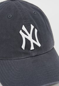 Casquette bleu marine en twill de coton avec un logo "NY" brodé en blanc à l'avant et une surface texturée subtile.