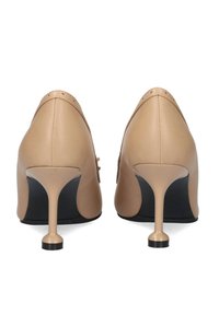 Zapatos de tacón alto de cuero color nude con punta afilada y un diseño de tacón esculpido único; textura suave y acento en la suela negra.
