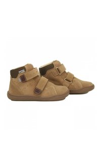 Stivaletti alla caviglia in suede color tan con due strappi in Velcro, un colletto in tessuto marrone strutturato e cuciture a contrasto. Suole in gomma flessibile per il comfort.