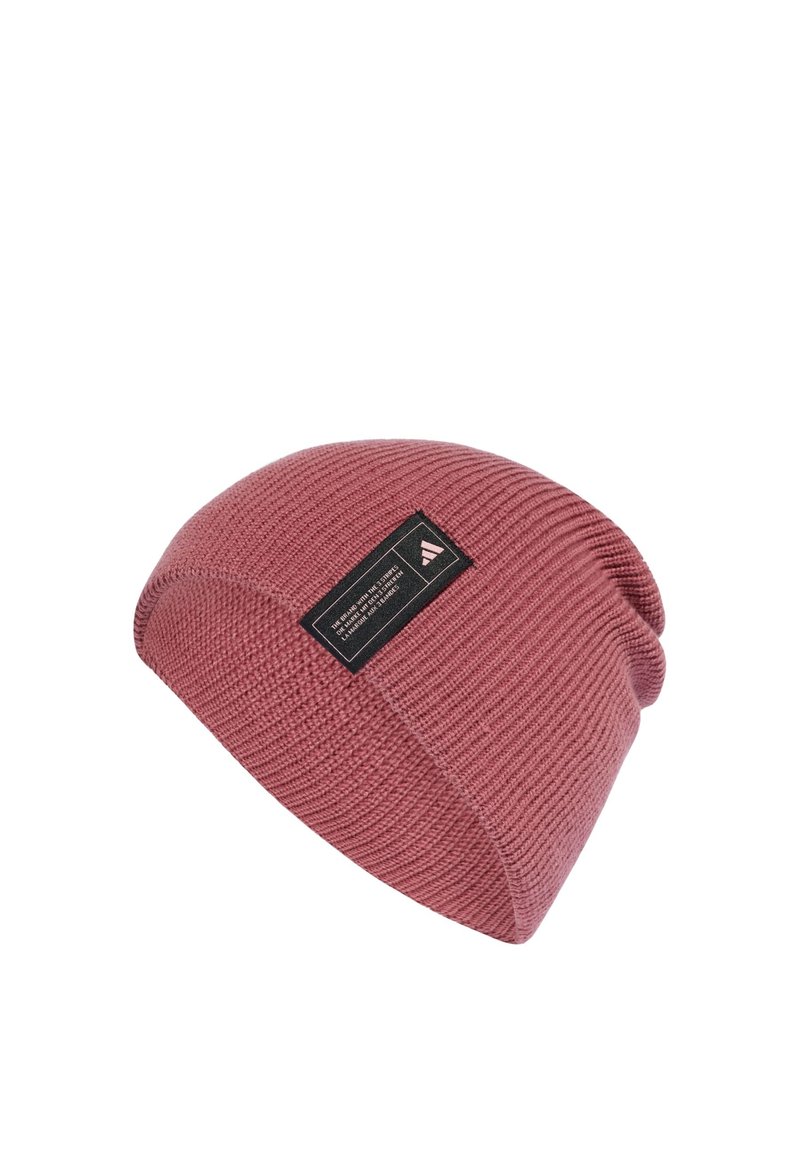 Dziany beret w kolorze kurzu różowego z teksturowym wzorem. Posiada czarną metkę z boku z białym tekstem i logo.