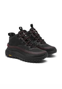 Bottes de randonnée noires avec un dessus texturé, des accents rouges et des lacets proéminents. Semelle extérieure Vibram pour l'adhérence, col rembourré et détails de logo.