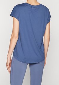 Blue athletic t-shirt with cap sleeves, smooth texture, rounded hem, and "ONLY PLAY" logo near the neckline. Paired with matching leggings.