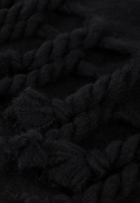 Svart stickad tyg med tjock, tvinnad garn som har en mjuk textur och ett tätt, åtsittande utseende, perfekt för värme och komfort.