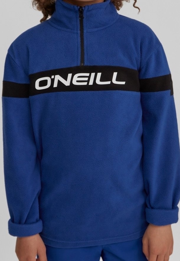 Enfant portant un pull polaire bleu avec une bande noire sur la poitrine et un logo blanc "O'NEILL", manches longues retroussées aux poignets.
