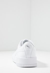 Baskets blanches avec une tige en cuir lisse, des accents texturés, un col rembourré et une semelle en caoutchouc avec un détail de logo sur le talon.