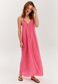 Ružová maxi šaty s ramienkami, V-výstrihom a textúrovaným lemom pozdĺž prednej časti. Vyrobené z ľahkého materiálu, dĺžka po členky, voľný strih.