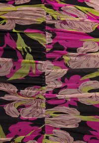 Floral dress fabric features black base with large pink and green flowers. Material is textured with gathered sections.