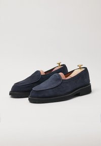 Navy suede slip-on shoes with a rounded toe, contrast piping, leather lining, and gold hardware accents. Sturdy black rubber sole.