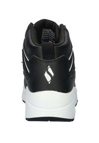 Zwarte synthetische schoen met een witte zool. Heeft een gevoerde kraag, een prominent logo op de hak en contrasterende witte strepen langs de zijkanten.