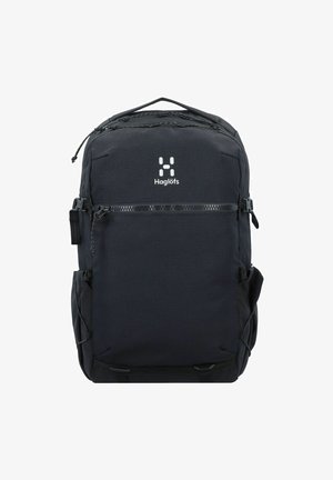 Mochila negra hecha de tela duradera, que presenta un bolsillo delantero con cremallera, bolsillos laterales de malla y una asa en la parte superior. Logo mostrado de manera prominente.