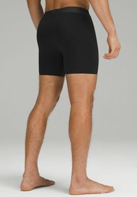 Zwarte boxershorts gemaakt van een gladde, rekbare stof met een comfortabele tailleband, gezien van de achterkant, benadrukt de pasvorm en het ontwerp.