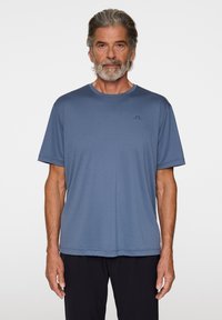 Blå t-shirt med kort ärm i lättviktsmaterial. Har en rund halsringning och en subtil logotyp på bröstet, med en avslappnad passform.