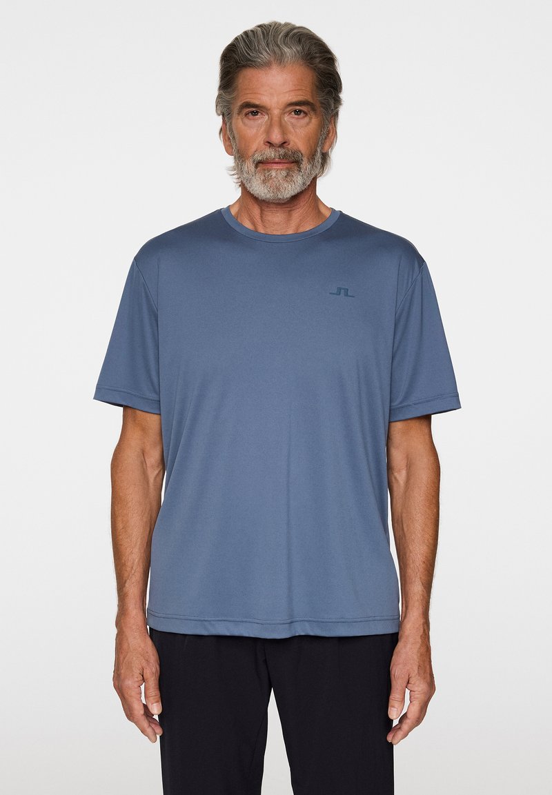 Blå t-shirt med kort ärm i lättviktsmaterial. Har en rund halsringning och en subtil logotyp på bröstet, med en avslappnad passform.