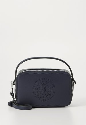 Porte-monnaie en cuir marine avec fermeture zip, détail de logo circulaire et une sangle détachable. Texture lisse et forme rectangulaire.