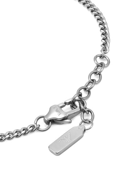 Bracelet en chaîne argentée composé de maillons ovales entrelacés, avec un fermoir sécurisé et une étiquette portant un logo, présentant une finition métallique polie.