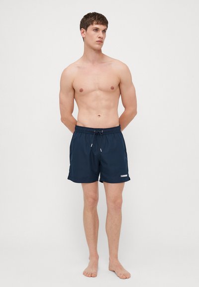 Shorts de bain bleu marine en tissu léger, dotés d'une taille élastique avec cordon de serrage et d'un petit logo sur la jambe gauche.