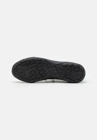 Suela de zapatilla atlética negra con patrones de agarre texturizados, incluidos diseños en zigzag y un logo. El material parece ser de goma con un acabado mate.