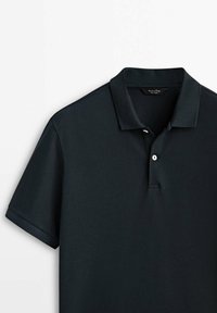 Polo marine en tissu tricoté texturé, avec un col classique et une patte de boutonnage à deux boutons. Manches courtes et sans motifs ni accents.