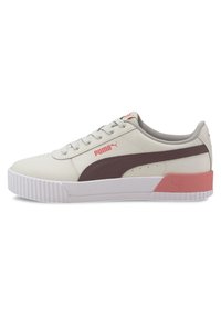 Baskets Puma en beige clair avec une bande marron, présentant un accent rose au talon, tige en cuir texturé et semelle en caoutchouc blanche.