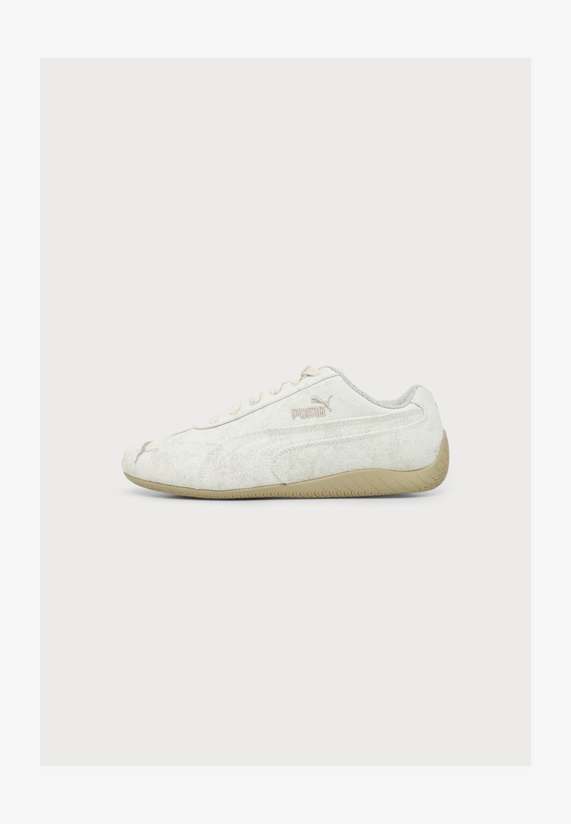 Baskets blanches Puma avec semelle beige, vue latérale, montrant le logo Puma et un design minimaliste sur un fond clair uni.