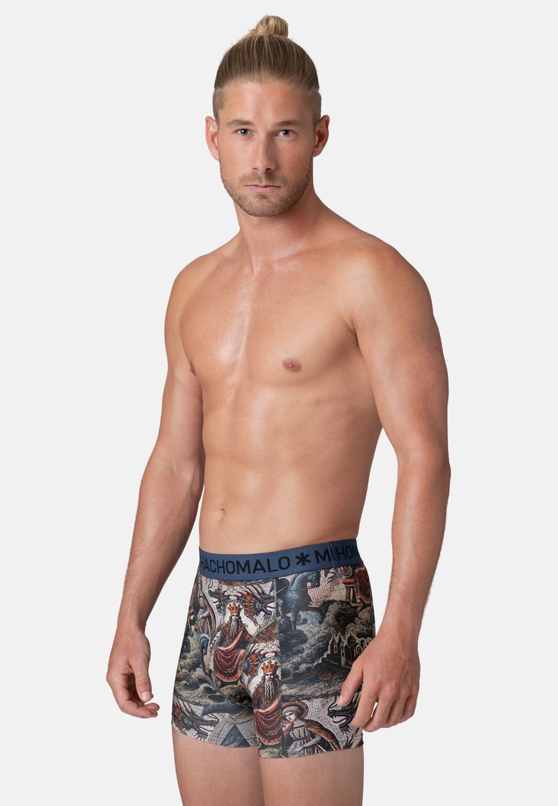Moške bokserice z modrim elastičnim pasom, ki vsebujejo podrobne, barvite vzorce figuralnih in pokrajinskih motivov na temnem ozadju.