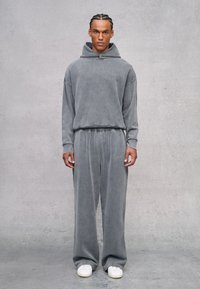 Grijze bijpassende hoodie en sweatpants set, gemaakt van zachte stof. Beschikt over een relaxed fit, kangoeroezak en geborduurd logo detail.